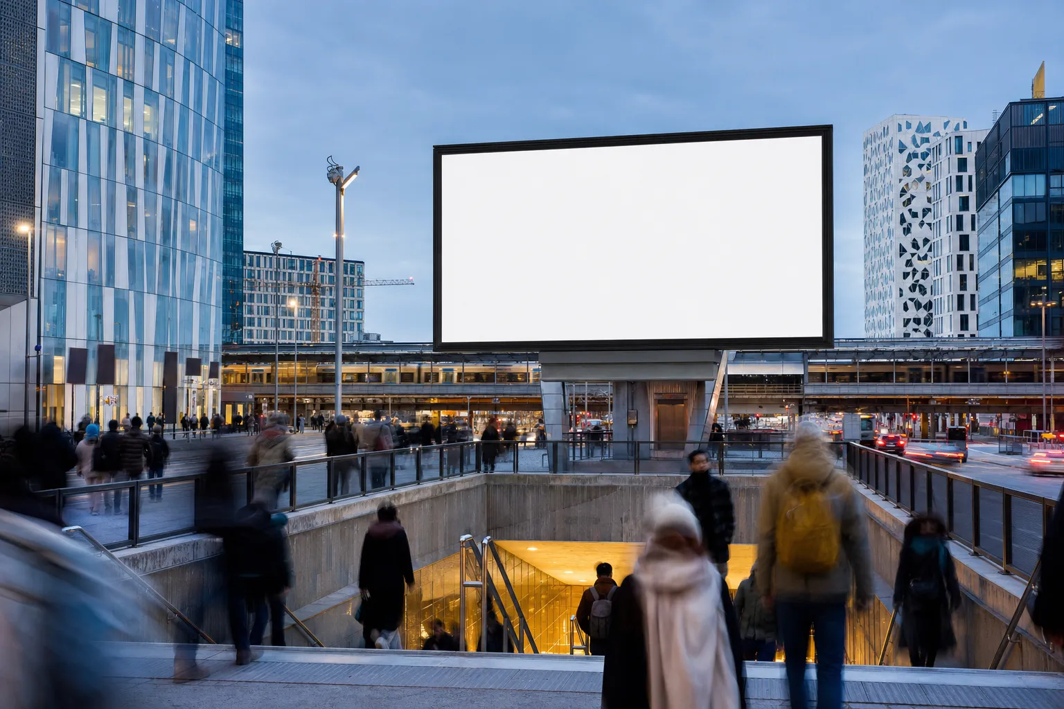 En stor tom digital reklamtavla ovanför ett livligt nordiskt stationstorg i skymningen, med förbipasserande i rörelseoskärpa nedanför.