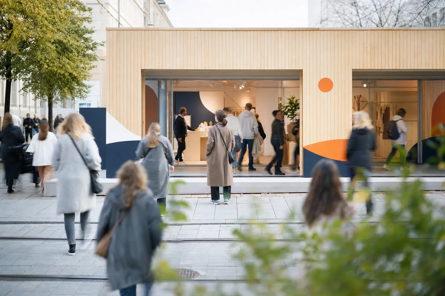 En stilren tillfällig pop-up-butik på en livlig stadsgata, där förbipasserande stannar till och kliver in, i rörelseoskärpa.