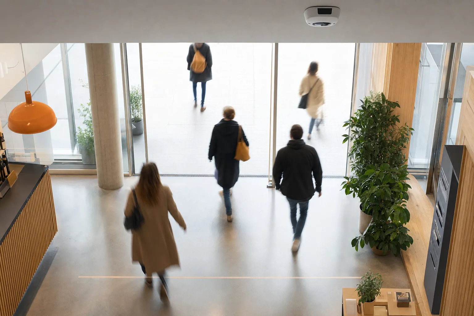 Vue depuis l'intérieur d'une entrée de magasin : un capteur optique 3D au plafond compte les clients franchissant une ligne entrée/sortie, en flou de mouvement, sans visages reconnaissables.