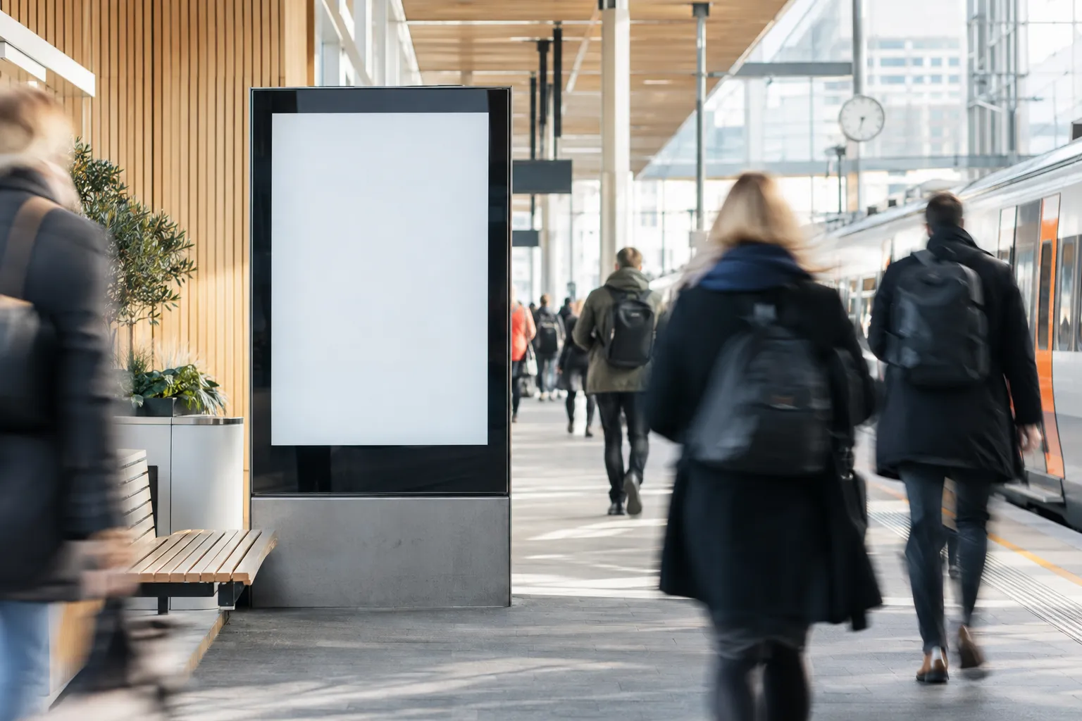 Digital reklameskjerm på en perrong med pendlere