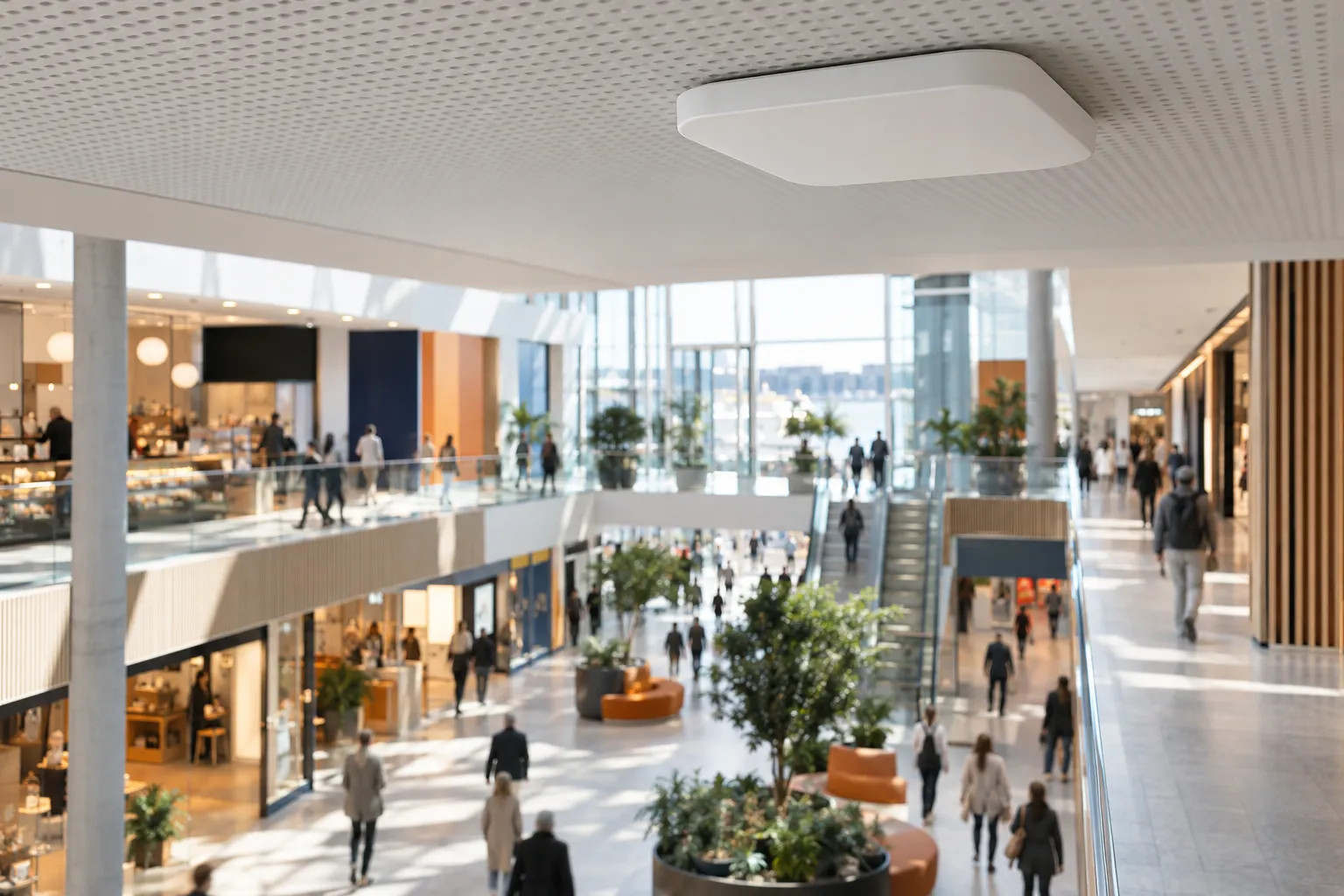 Et takmontert Wi-Fi-aksesspunkt over kunder i bevegelse gjennom et lyst kjøpesenter, med bevegelsesuskarphet.
